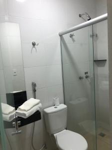 a bathroom with a toilet and a glass shower at Victor Plaza Formiga in Formiga