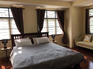 a bedroom with a bed and a couch and windows at Ban Soi San Sook Homestay in Songkhla