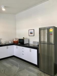 a kitchen with a stainless steel refrigerator and a microwave at Ban Soi San Sook Homestay in Songkhla