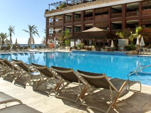 a swimming pool with chairs in front of a building at Gran Hotel Guadalpín Banus in Marbella