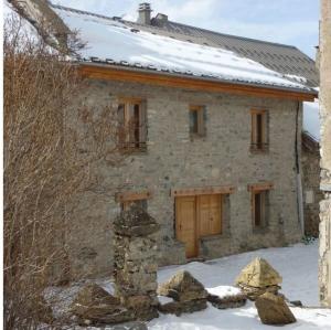 une maison en pierre avec de la neige devant elle dans l'établissement Les Cabasses 6 - Accommodation in a village house, à Villar-dʼArêne