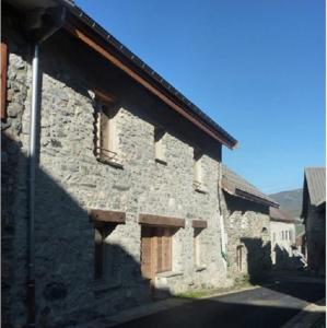 een stenen gebouw met twee ramen aan de zijkant bij Les Cabasses 6 - Accommodation in a village house in Villar-dʼArène