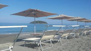 eine Gruppe von Stühlen und Sonnenschirmen am Strand in der Unterkunft B&B La Stazione in Diamante