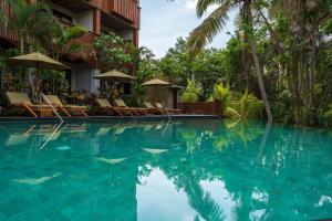 basen z leżakami i parasolami obok ośrodka w obiekcie Adiwana Unagi Suites w mieście Ubud