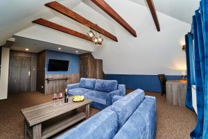 ein Wohnzimmer mit einem blauen Sofa und einem Tisch in der Unterkunft Gościniec pod Strzechą in Suwałki