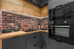 een keuken met zwarte apparatuur en een bakstenen muur bij Apartments Warsaw Markowska by Renters in Warschau