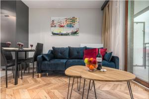 een woonkamer met een blauwe bank en een tafel bij Apartments Warsaw Markowska by Renters in Warschau