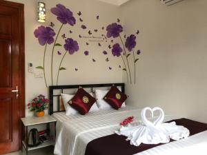 - une chambre avec un lit orné de fleurs violettes sur le mur dans l'établissement Thăng Loan Tam Cốc Hostel, à Ninh Binh