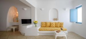 a white living room with a couch and a tv at Above Blue Suites in Imerovigli