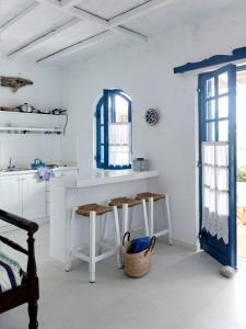 a white kitchen with a counter and stools in it at Villa Ippocampi - Adults Only in Hersonissos