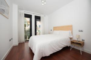 - une chambre blanche avec un grand lit et une fenêtre dans l'établissement Ferrandiz Suite, à Malaga