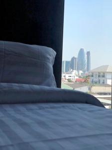 a bed with a pillow and a view of a city at The LOCAL Ari in Bangkok