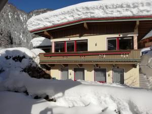 a house covered in snow in front at Ferienwohnung Kogler in Waidring