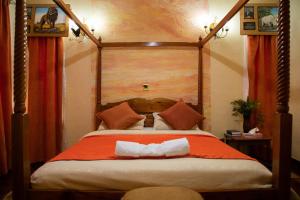 ein Schlafzimmer mit einem großen Bett mit einer orangefarbenen Decke in der Unterkunft Sangare Gardens in Mweiga