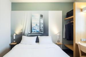 ein Schlafzimmer mit einem großen weißen Bett und einem Fenster in der Unterkunft B&B HOTEL Saint-Michel sur Orge in Saint-Michel-sur-Orge