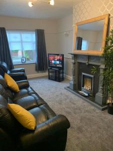 sala de estar con sofá de cuero y chimenea en Newfield House en Crewe