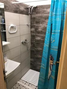 a shower with a blue shower curtain in a bathroom at Leptir in Zagreb