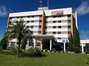 a hotel building with a palm tree in front of it at Hotel Campo Largo Express in Campo Largo
