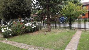 una cerca con un árbol y flores en un patio en Departamentos Berna, en Valdivia