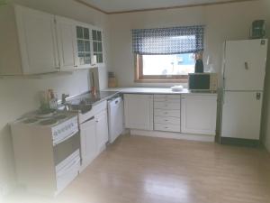 uma cozinha com armários brancos, um lavatório e um frigorífico em Kristian 4. Gt. apartement em Vardø