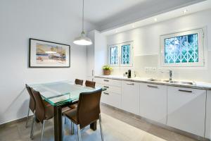 cocina con armarios blancos, mesa y sillas en Boutique77 Luxury Apartment, en Atenas