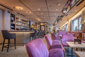 a restaurant with purple chairs and a bar at Der Rindererhof in Tux