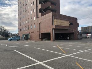 un parcheggio vuoto di fronte a un edificio di mattoni di AZ Inn Handa Inter a Handa