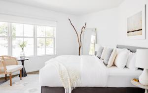 a white bedroom with a white bed and a chair at The Menhaden Hotel in Greenport