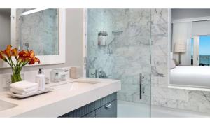 a white bathroom with a sink and a shower at La Playa Beach & Golf Resort, a Noble House Resort in Naples