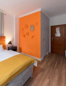 Habitación de hotel con cama y pared de color naranja en TCZ Mokra, en Poznan
