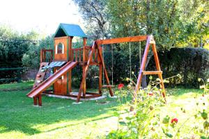 un parque infantil de madera con un tobogán en el césped en Cabañas Calderón I en San Rafael