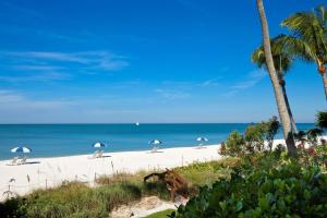 a beach with chairs and umbrellas and the ocean at La Playa Beach & Golf Resort, a Noble House Resort in Naples