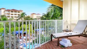 a balcony with a chair and a table and a pool at La Playa Beach & Golf Resort, a Noble House Resort in Naples