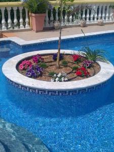 een tuin in een zwembad met een boom en bloemen bij Villa Sesmarias Lux is a Luxury villa with private swimming poolm sea-views and AC in Carvoeiro