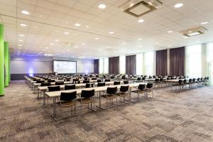 a conference room with tables and chairs and a screen at Novotel Düsseldorf City West in Düsseldorf