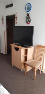a television on a wooden stand with a chair and a table at Happy apartment in Zalakaros