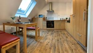 eine Küche mit Holzböden, einem Tisch und einem Fenster in der Unterkunft DIE Mansarde ! in Saarbrücken