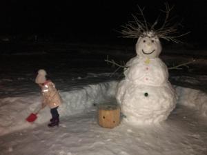 een persoon die naast een sneeuwpop staat in de sneeuw bij Alpine Chalet in Santa Caterina Valfurva