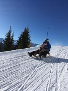 two people riding on a sled down a snow covered slope at Ferienwohnung Soller in Bramberg am Wildkogel