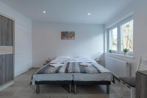 a white bedroom with a bed and a window at Pokoje Nad Święcajtami in Ogonki