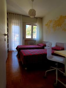 um quarto com 3 camas, uma secretária e uma mesa em Arianna Apartments em Vittorio Veneto