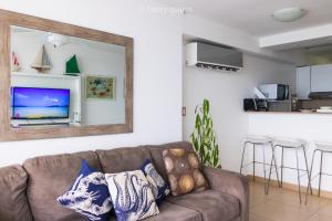 - un salon avec un canapé brun et un miroir dans l'établissement Apartamento El Palmar Residences, à San Carlos
