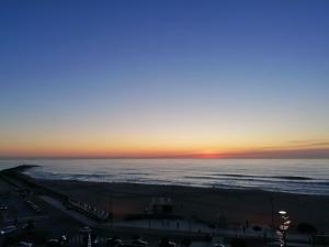 um pôr-do-sol sobre o oceano e a praia em THE ONE Grand Hotel da Póvoa na Póvoa do Varzim