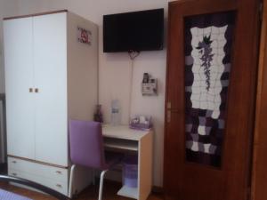 ヴェローナにあるVerona Bottego Guest Houseのデスクと紫の椅子が備わる客室です。