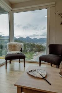 a living room with two chairs and a large window at Ushuaia Homes Martial Apartments in Ushuaia