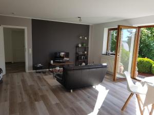 ein Wohnzimmer mit einem schwarzen Sofa und einem Tisch in der Unterkunft Garden & Hill Ferienwohnung Limburg in Simmerath