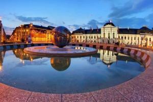 a fountain in the middle of a city at night at Queen Flat in Old Town with Castle view in Bratislava