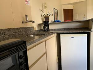 a kitchen with a stove top oven and a sink at Cheverny Apart Hotel in Belo Horizonte