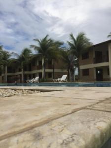 a swimming pool with two chairs and palm trees at Club house in Prainha