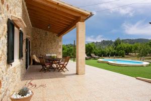 een patio met een tafel en stoelen en een zwembad bij Coqueta in Caimari